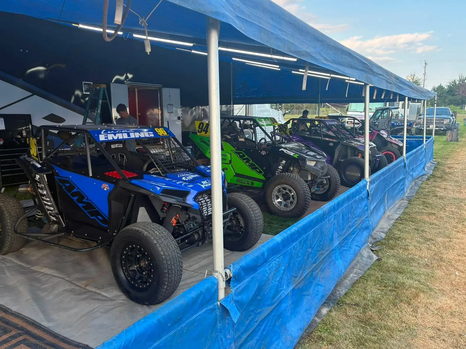 Race side-by-sides lined up under the pit canopy