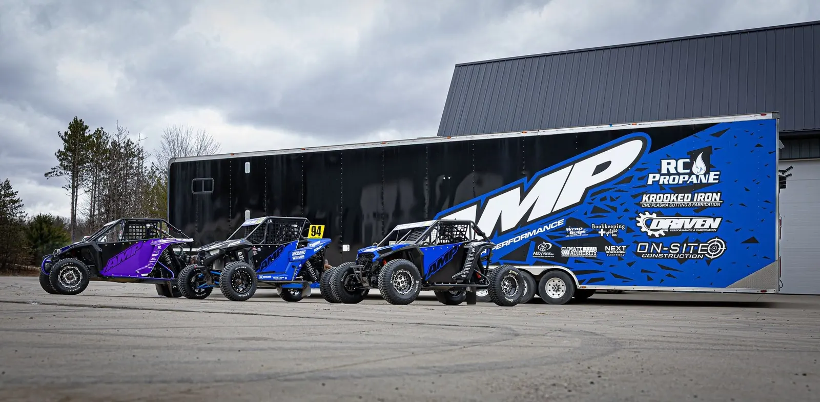 AMP race trailer with three race side-by-sides in AMP colors