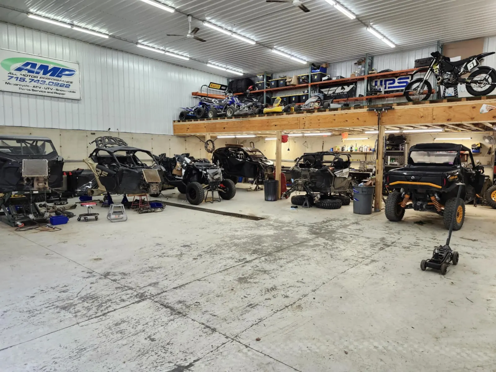 Service bay with side-by-sides and dirt bikes on a mezzanine