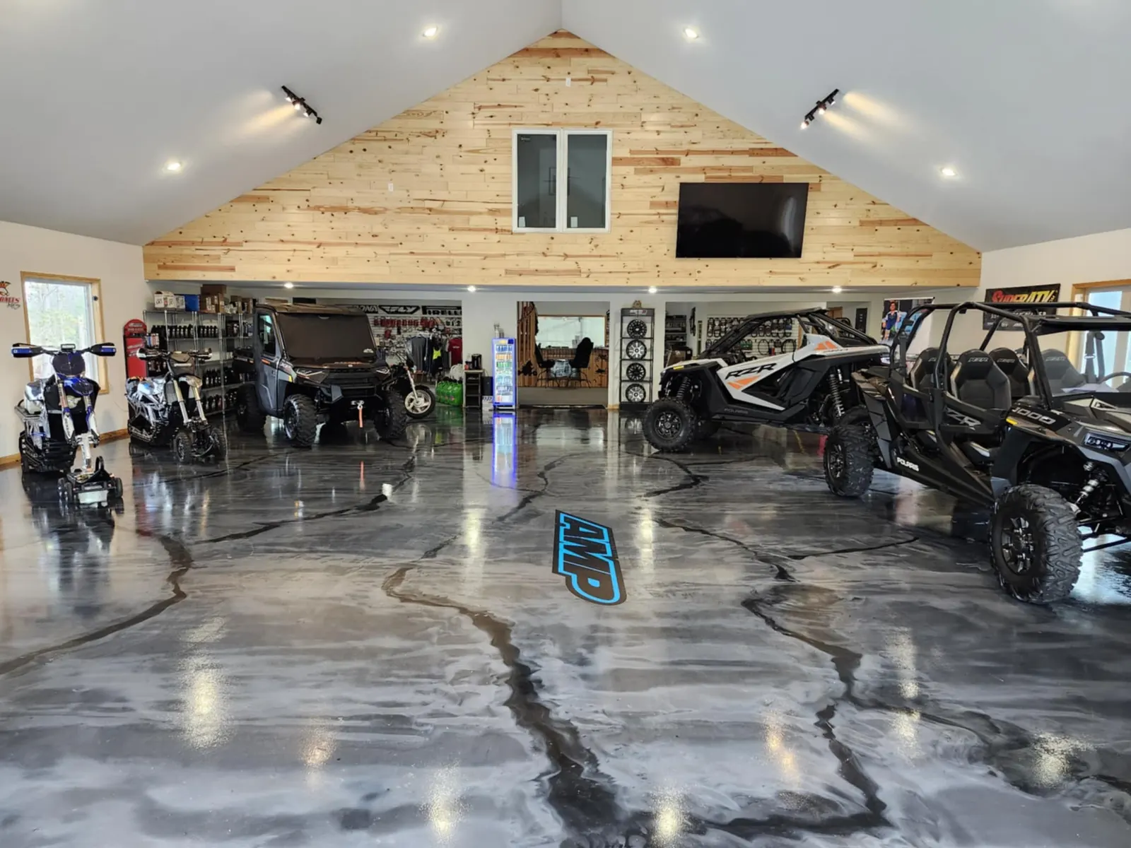 Showroom with the AMP logo on a polished epoxy floor and side-by-sides on display